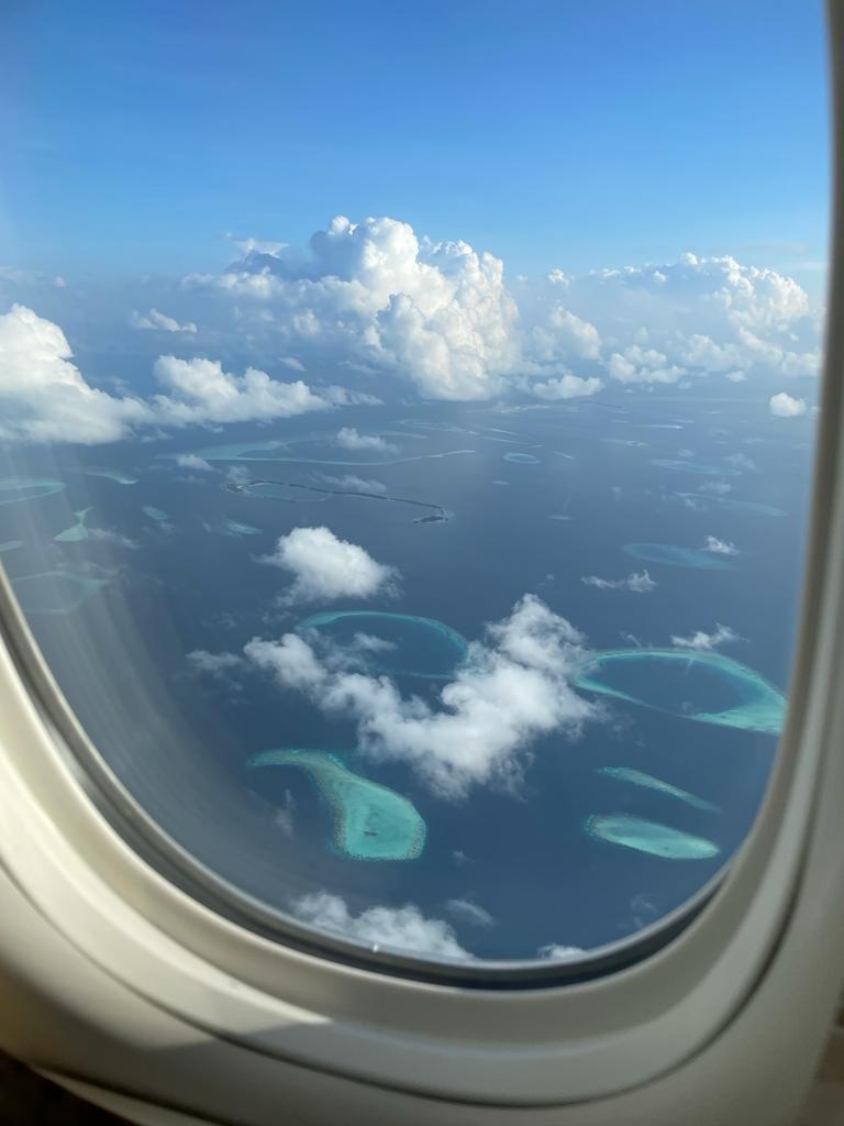 Blick aus dem Flugzeug auf die von türkisfarbenen Lagunen umgebenen Inseln